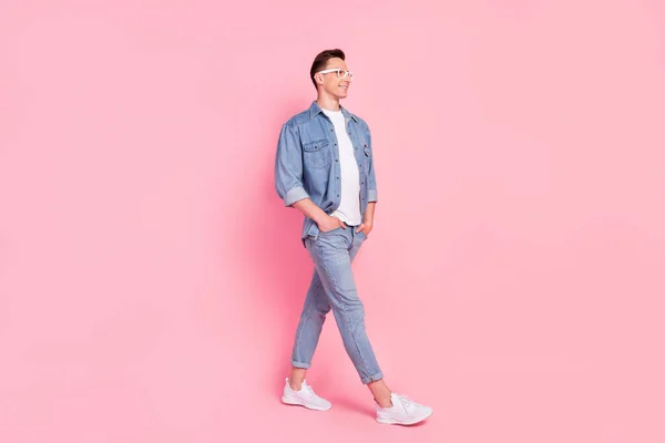 Full size profile side photo of young cheerful confident man go walk wear glasses isolated on pink color background — стоковое фото