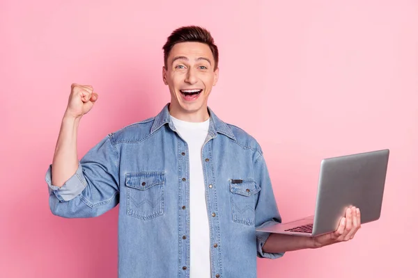 Фото счастливого хорошего настроения возбужденный сумасшедший бизнесмен поднять кулак в триумфе успеха провести ноутбук изолированы на розовом фоне цвета — стоковое фото