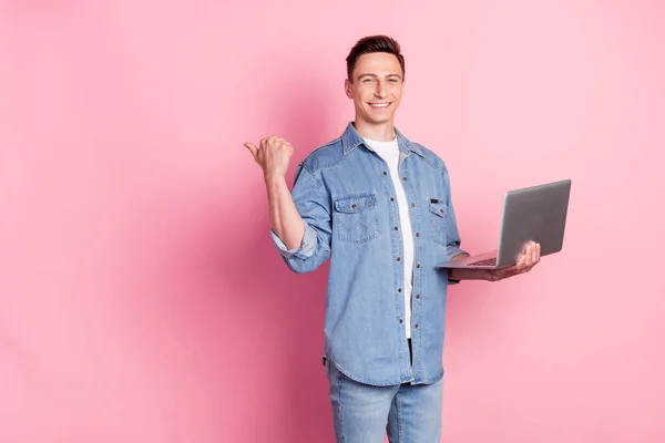 Foto de joven sonriente empresario fresco mantenga portátil dedo copyspace anuncio recomienda aislado en el fondo de color rosa —  Fotos de Stock