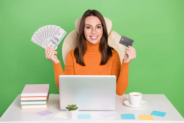 Portrait of attractive trendy cheerful girl manager working remotely holding cash bank card buying order isolated over bright green color background — Stock Photo, Image