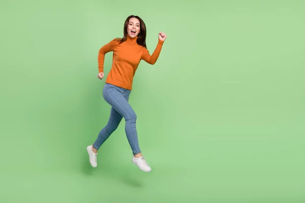 Longitud completa vista del tamaño del cuerpo de la atractiva chica alegre confiada saltando acción de movimiento corriendo aislado sobre fondo de color verde brillante — Foto de Stock