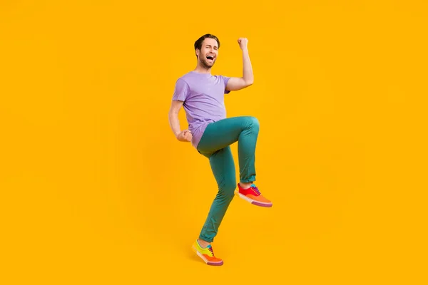 Foto di ragazzo fortunato stupito celebrare la vittoria indossare viola t-shirt pantaloni scarpe da ginnastica isolato colore giallo sfondo — Foto Stock