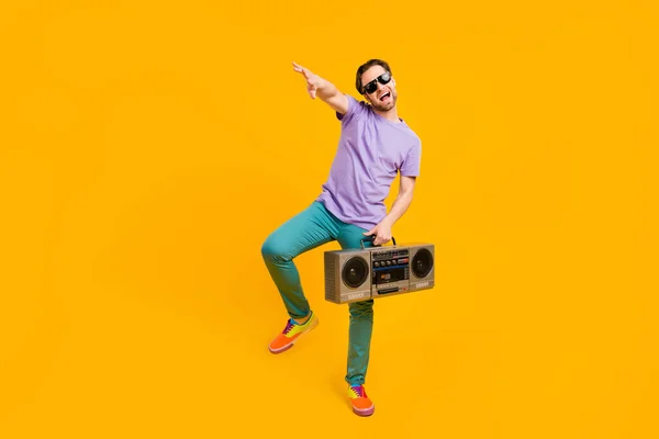 Foto de divertido funky guy hold boom box dance disfrutar discoteca desgaste violeta camiseta aislado color amarillo fondo — Foto de Stock