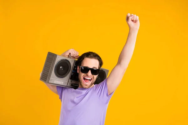 Fotografie zapůsobilo štěstí mladý muž oblečený fialové tričko tmavé brýle tanec boombox izolované žluté barvy pozadí — Stock fotografie