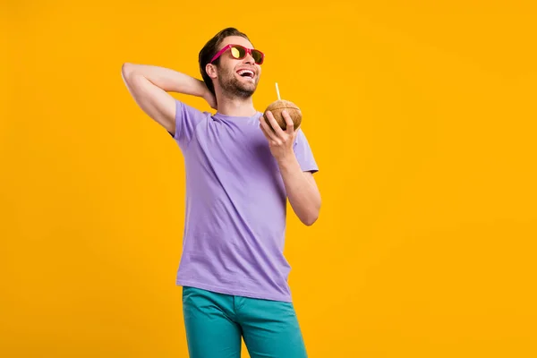Foto de chico dulce funky vestido púrpura camiseta gafas oscuras beber agua de coco espacio vacío sonriendo aislado color amarillo fondo — Foto de Stock