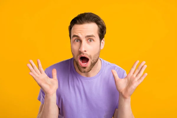 Фото безмолвного шокированного парня поднять руки omg реакция носить фиолетовые футболки изолированный желтый цвет фона — стоковое фото