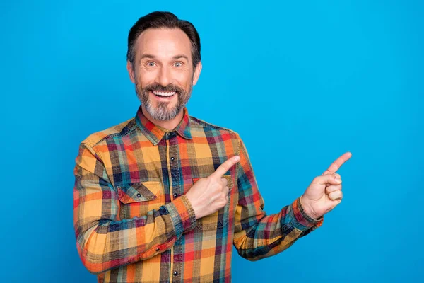 Photo portrait homme souriant doigt pointant copyspace portant chemise à carreaux isolé fond de couleur bleue vibrante — Photo