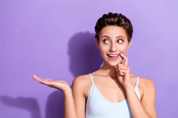 Foto retrato menina em azul top mostrando espaço em branco na palma pensativo isolado pastel cor violeta fundo — Fotografia de Stock