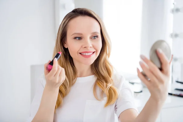 Retrato de chica alegre atractiva mirando el espejo haciendo maquillaje aplicando bálsamo en el hogar blanco claro en el interior —  Fotos de Stock