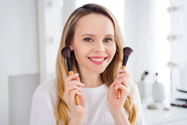 Foto retrato mujer joven en pijama blanco haciendo maquillaje con cepillos en la mañana — Foto de Stock