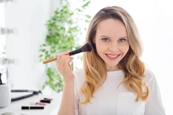 Foto retrato mujer joven en ropa blanca haciendo maquillaje aplicar iluminador con cepillo — Foto de Stock