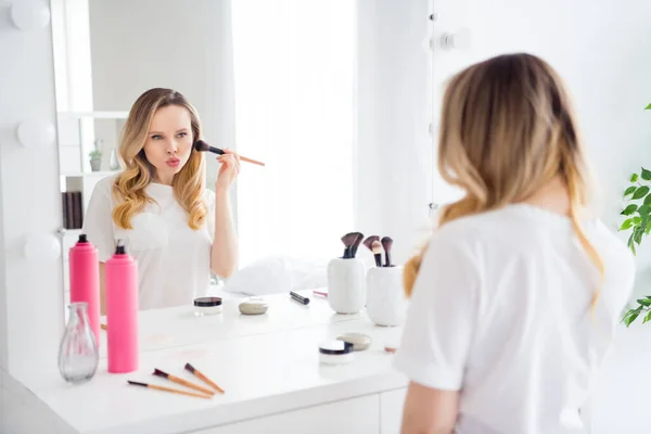 Foto retrato mujer joven en ropa blanca aplicando polvo con cepillo cerca del espejo enviando beso de aire labios enfurecidos — Foto de Stock