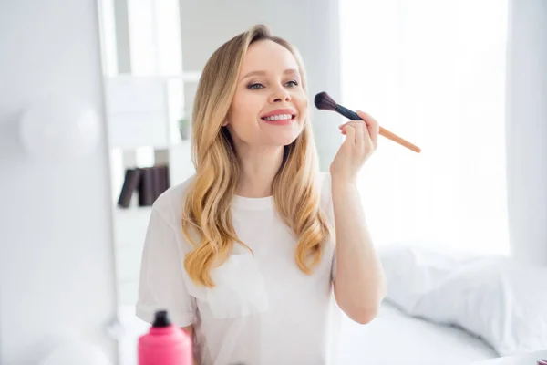 Foto retrato mujer joven en ropa blanca aplicando polvo con cepillo cerca del espejo —  Fotos de Stock