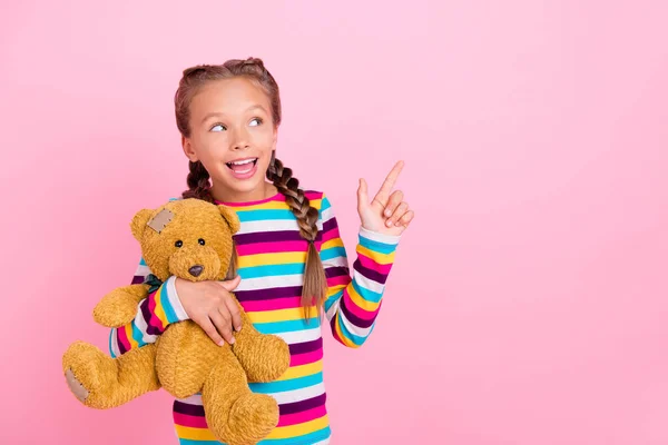Фото игривой леди обнимать игрушку медведя прямой палец пустое пространство посмотрите вверх носить полосатую рубашку изолированный розовый цвет фона — стоковое фото