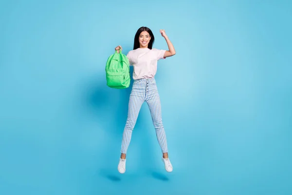 Teljes hossz testméret kilátás elég vidám tini lány jumping holding bag szórakozás elszigetelt felett élénk kék színű háttér — Stock Fotó