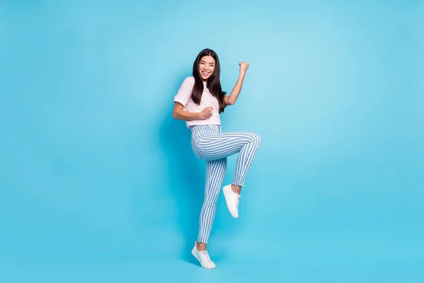 Foto de longitud completa de alegre bastante agradable joven mujer levantar el puño ganador celebrar aislado en el fondo de color azul —  Fotos de Stock