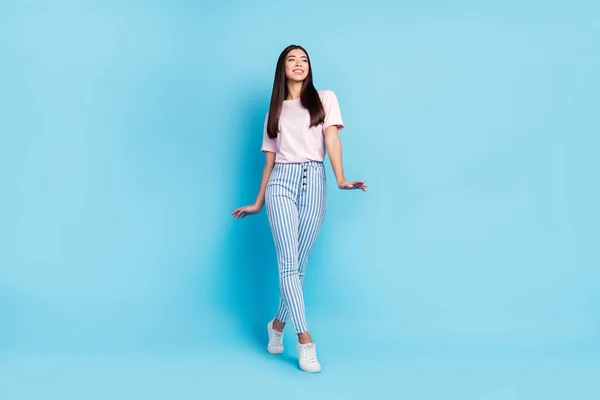 Full size foto van jong aantrekkelijk meisje gelukkig positief glimlach kijk leeg ruimte gaan lopen geïsoleerd over blauwe kleur achtergrond — Stockfoto