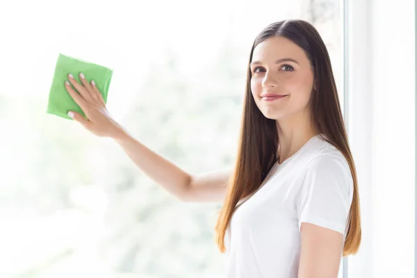 Portrait of attractive cheerful girl wiping window cleansing tidying up glass at light white home indoors — Stock Photo, Image