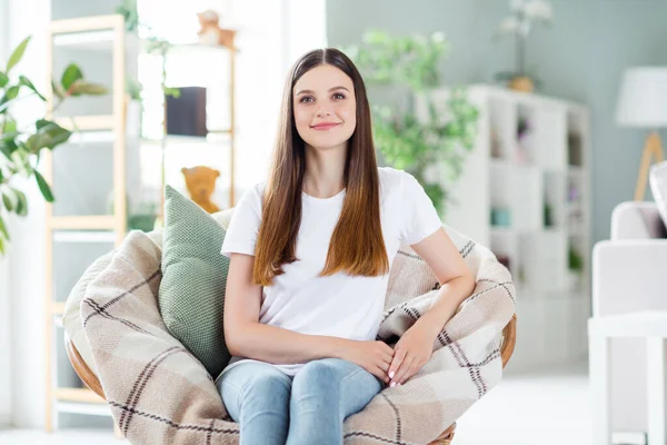 Portret van een aantrekkelijk vrolijk meisje zittend in een stoel rustend en een rustige dag eenzaam doorbrengend in de woonkamer binnenshuis — Stockfoto