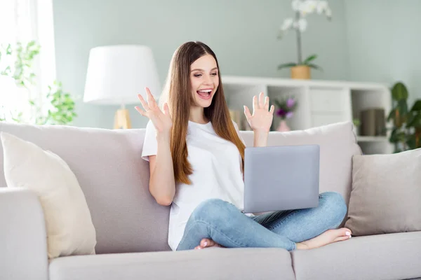 Retrato de chica afortunada alegre atractiva sentada en diván usando el ordenador portátil que se divierte en casa sala de estar en el interior —  Fotos de Stock