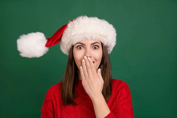 Photo de jeune fille attrayante heureux sourire positif couvrir bouche à main rire porter santa chapeau isolé sur fond de couleur verte — Photo