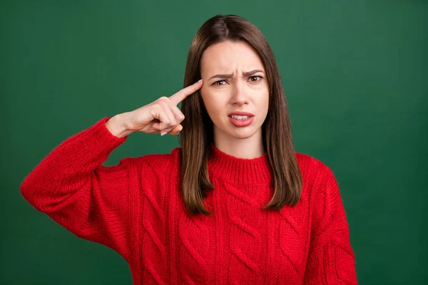 Foto retrato menina em pulôver vermelho culpando mantendo o dedo perto da testa isolado cor verde fundo — Fotografia de Stock