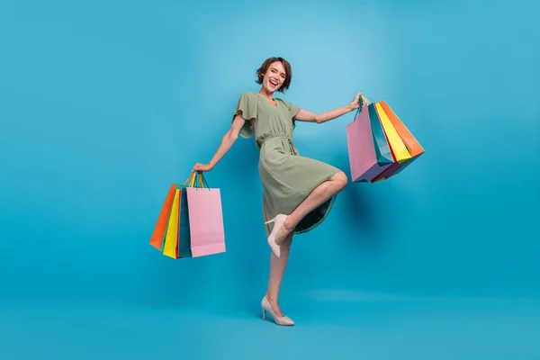 Teljes méretű fotó a pozitív vidám fiatal nő kézi bevásárló táskák eladása Mall elszigetelt kék színű háttér — Stock Fotó