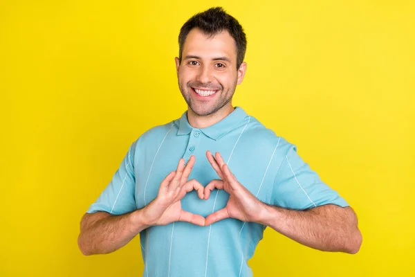 Bild av kokett brunett man visa hjärta bära blå t-shirt isolerad på gul färg bakgrund — Stockfoto