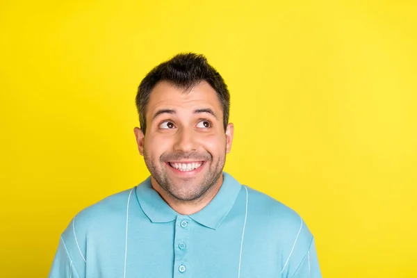 Photo de impressionné mignon jeune homme habillé bleu t-shirt souriant regardant vide espace isolé couleur jaune fond — Photo