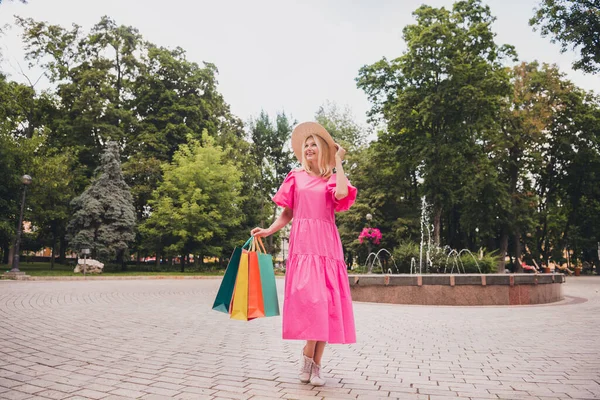 Full längd kropp storlek foto äldre kvinna med blont hår promenader med väskor skrattar efter shopping — Stockfoto