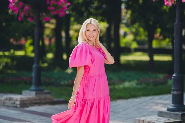 Foto von glänzenden entzückenden Rentnerin gekleidet rosa Kleidung zu Fuß lächelnd im Freien außerhalb der Stadt Straße — Stockfoto