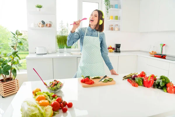 Retrato de menina alegre atraente preparando refeição cantando hit se divertindo em casa luz cozinha branca dentro de casa — Fotografia de Stock