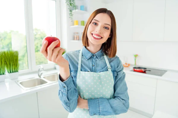 Ritratto di attraente ragazza allegra mangiare mela succosa trascorrere il giorno lavori domestici di fine settimana a casa luce cucina bianca — Foto Stock