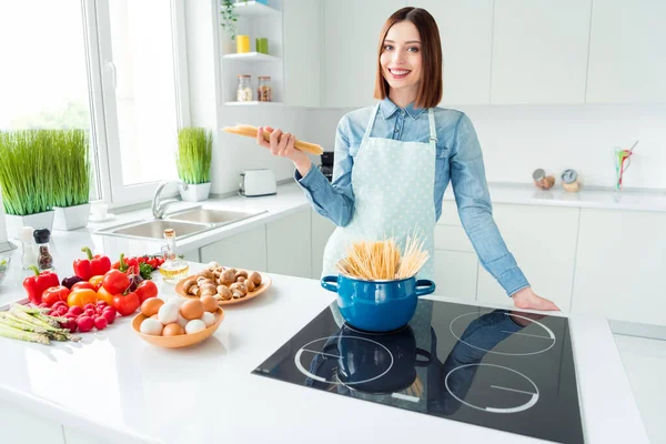 Fénykép portré mosolygós nő kötényben főzés spagetti zöldségekkel a konyhában — Stock Fotó