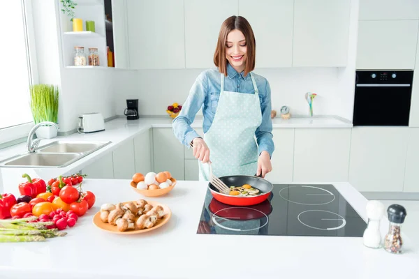 Foto portret lachende vrouw in schort koken omelet toevoegen van champignons — Stockfoto