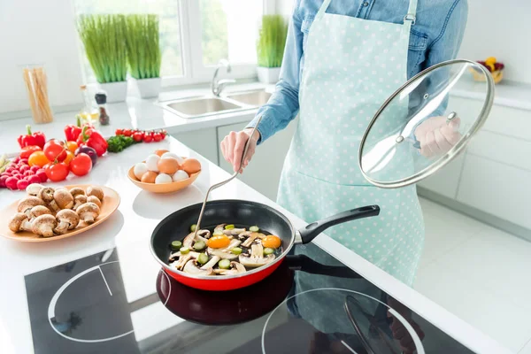 Przycięte zdjęcie kobieta w fartuchu przygotowuje omlet dodając grzyby — Zdjęcie stockowe