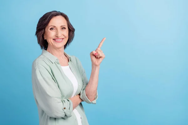 Fotoportrett senior kvinne smilende pekende finger blank plass isolert pastellblå farge bakgrunn – stockfoto