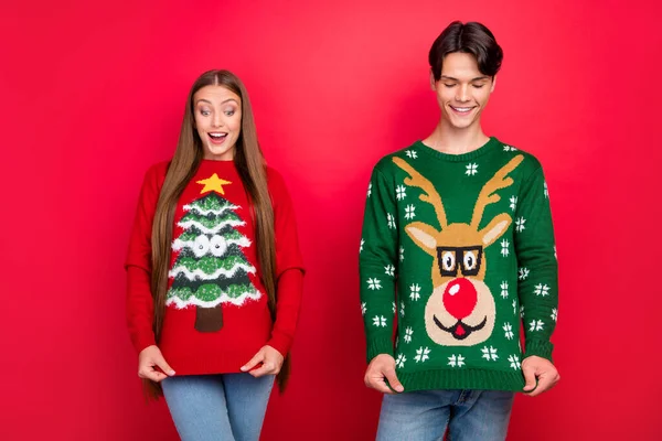 Photo of cheerful excited couple girl guy look ornament wear ugly pullover isolated red color background — Stock Photo, Image