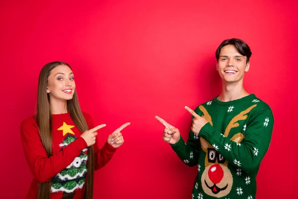 Foto von Promoter Paar zeigen Finger leer Raum Neuheit tragen hässlichen Pullover isoliert rote Farbe Hintergrund — Stockfoto