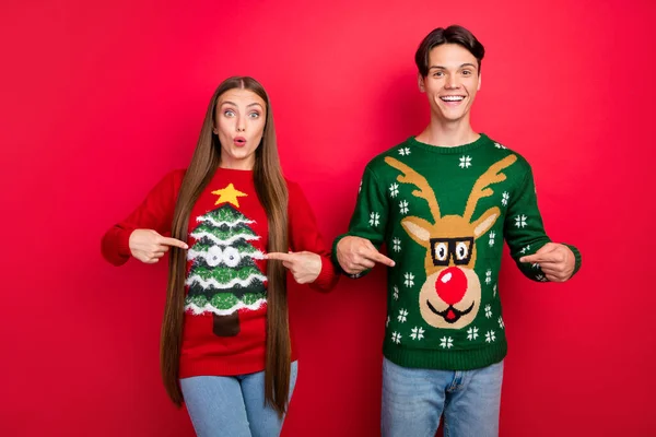 Photo of funny excited nice couple direct fingers outfit wear ugly pullover isolated red color background — Stock Photo, Image
