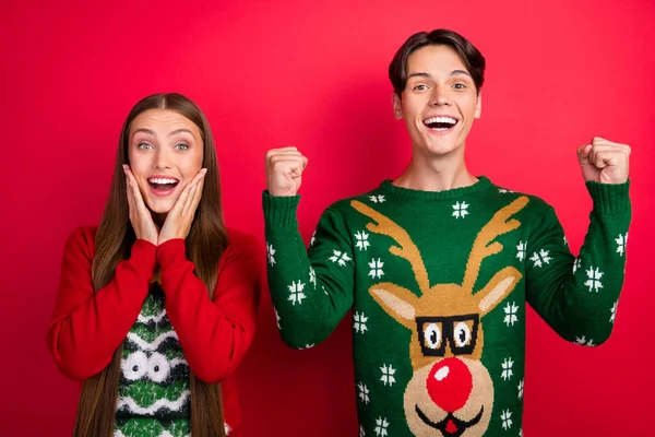 Photo of funky astonished two people celebrate victory attainment wear ugly sweater isolated red color background — Stock Photo, Image