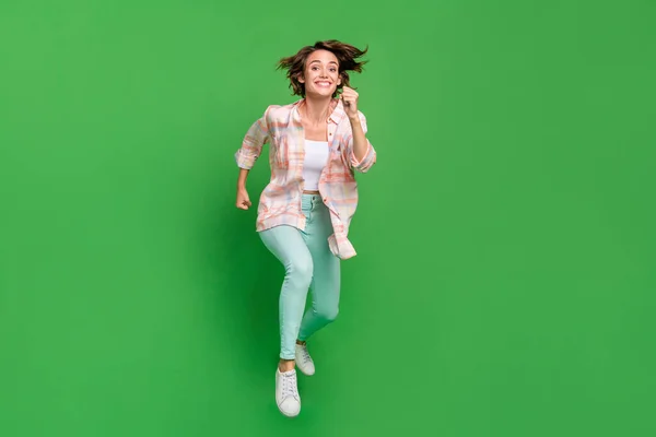 Pleine taille photo de joyeux positif heureux jeune femme sauter en l'air courir presser vente isolé sur fond de couleur verte — Photo
