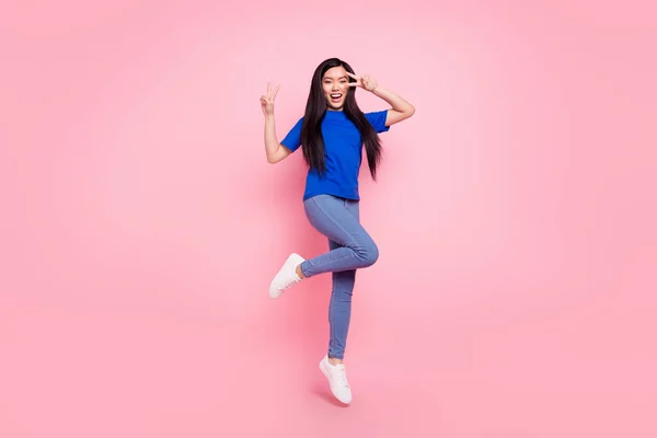 Foto de longitud completa de alegre mujer joven saltar hacer v-signos hola sonrisa aislada en el fondo de color rosa —  Fotos de Stock