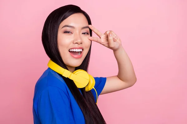 Foto de mujer feliz atractiva joven hacer v-signo usar auriculares relajarse aislado en el fondo de color rosa —  Fotos de Stock