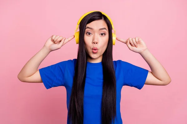 Foto de sorprendida mujer joven punta dedos auriculares escuchar música aislada en el fondo de color rosa —  Fotos de Stock