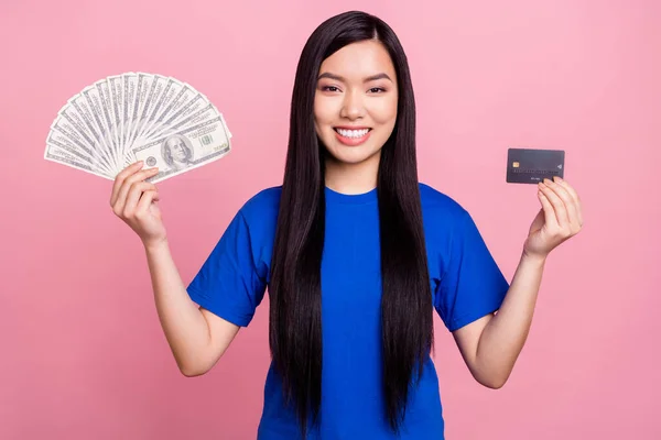 Photo positive jeune femme heureuse tenir la main argent comptant carte de crédit isolé sur fond de couleur rose — Photo