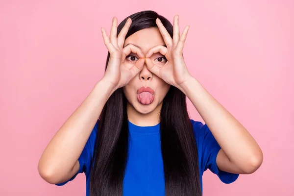 Foto av funky rolig ung positiv kvinna sticka ut tungan fingrar glasögon okej isolerad på rosa färg bakgrund — Stockfoto