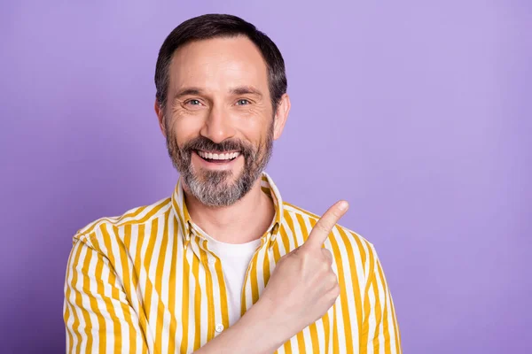 Photo of excited sweet mature man dressed striped shirt pointing finger empty space smiling isolated violet color background — Stock Photo, Image
