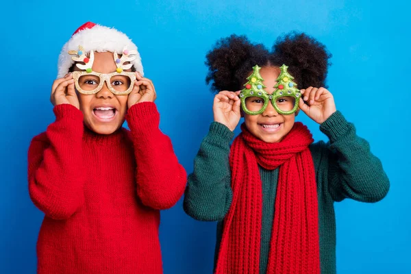 Foto de encantadores niños excitados de piel oscura usan jersey gafas de cabeza bufanda sonriente aislado color azul fondo —  Fotos de Stock
