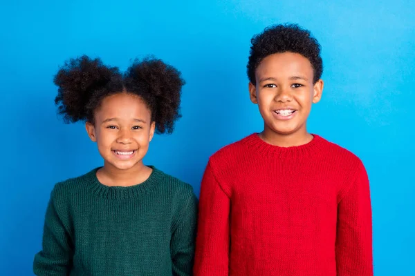 Фото смешной довольно темной кожи дети носят пуловеры улыбаясь изолированный синий цвет фона — стоковое фото